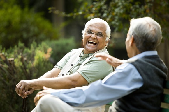 Two retired friends talking on a park bench. 