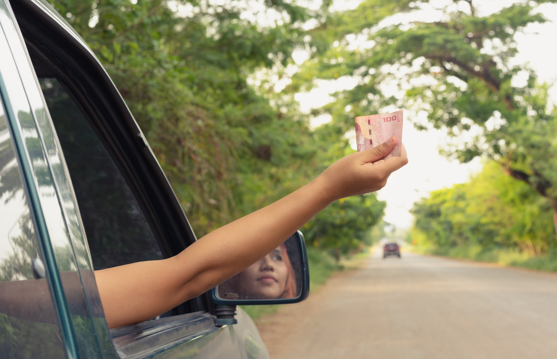 Car passenger holding cash out of the window.