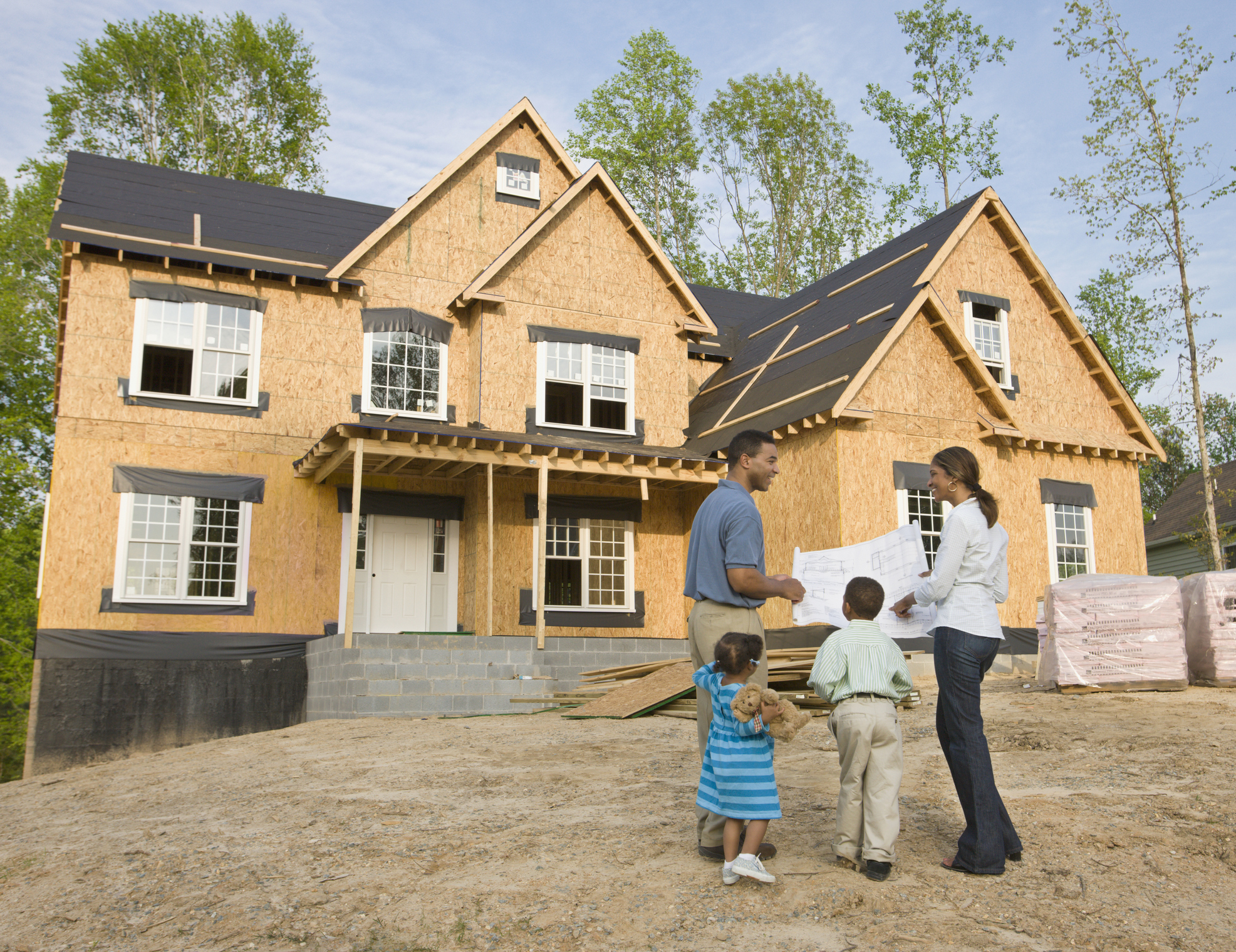A family stands in front of a house under construction.