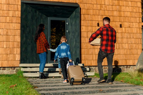 A family with luggage walking toward a home.