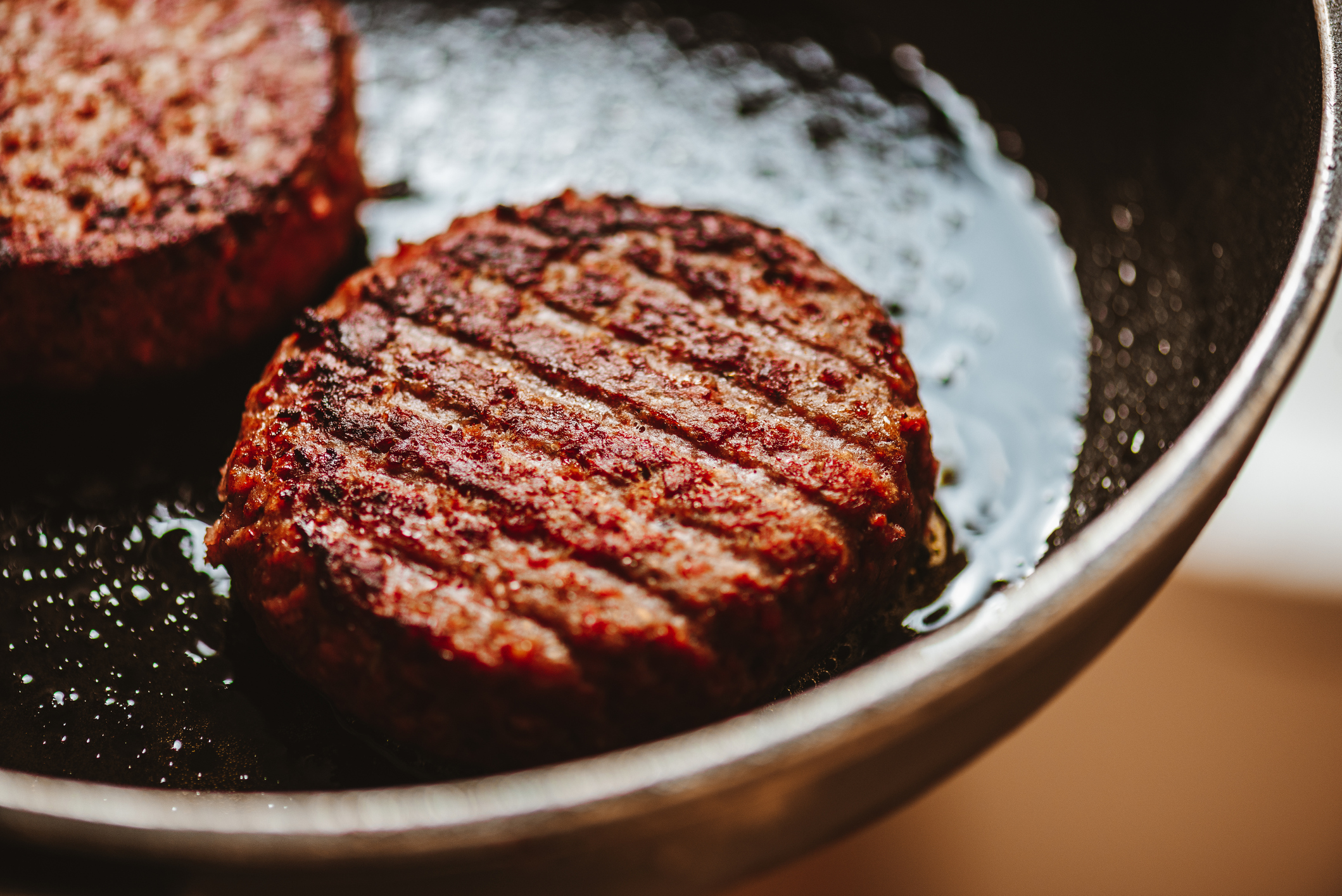 Plant-based burgers in a frying pan.