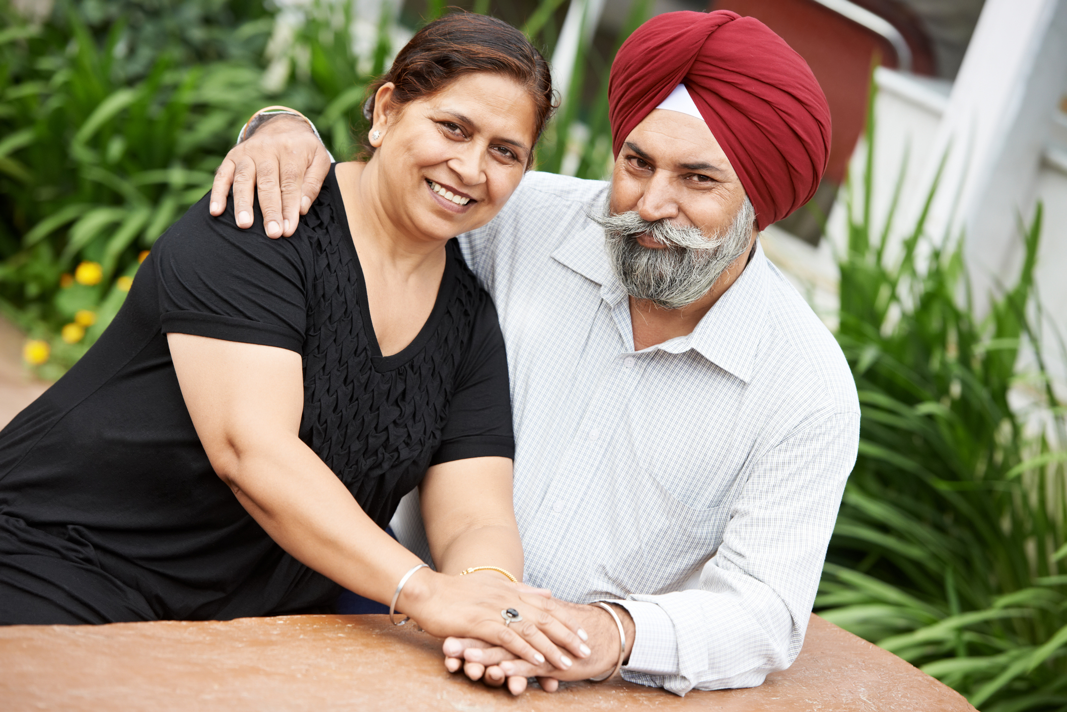Two smiling people looking at the camera and holding hands.