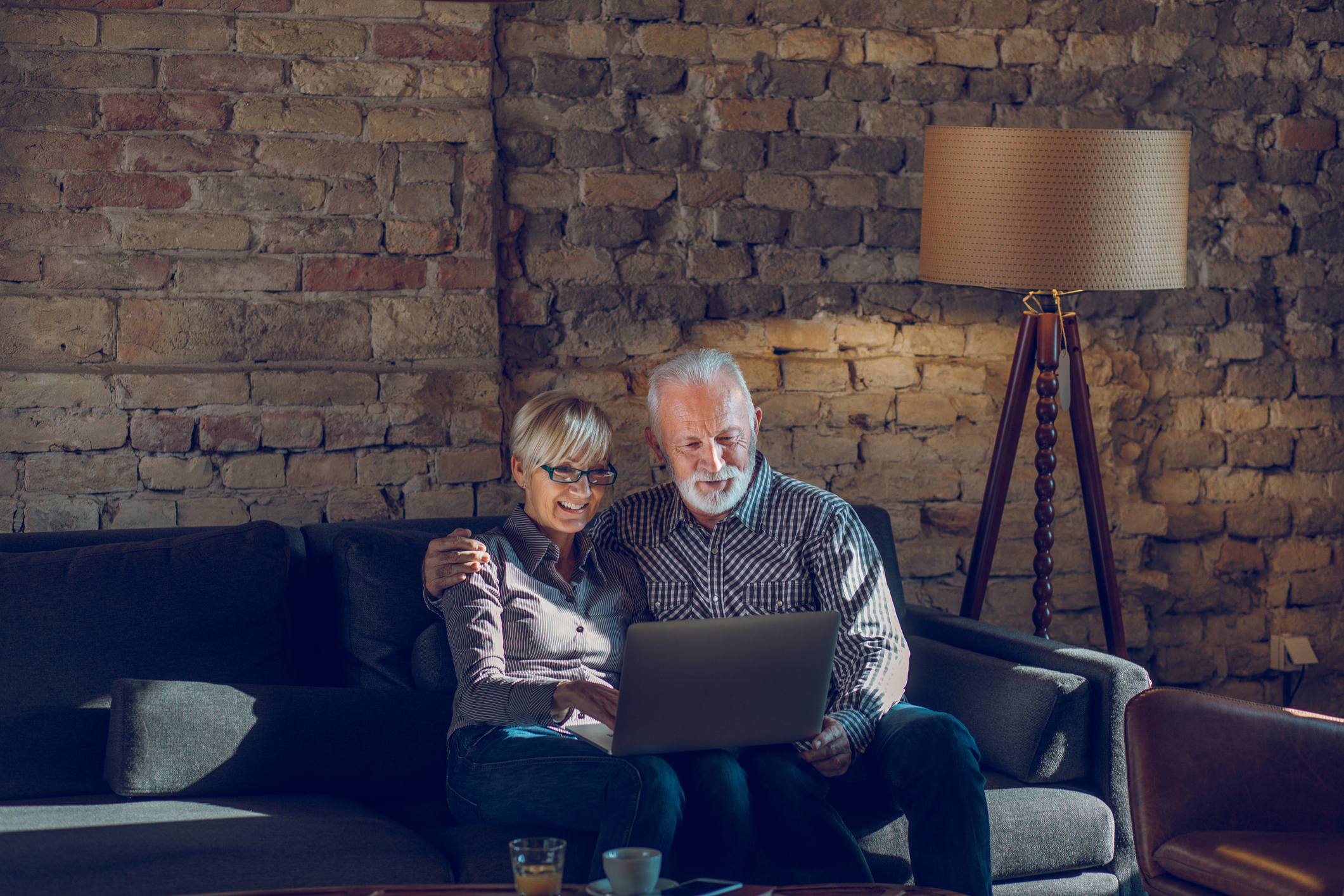 Two people sitting on a couch looking at a laptop.