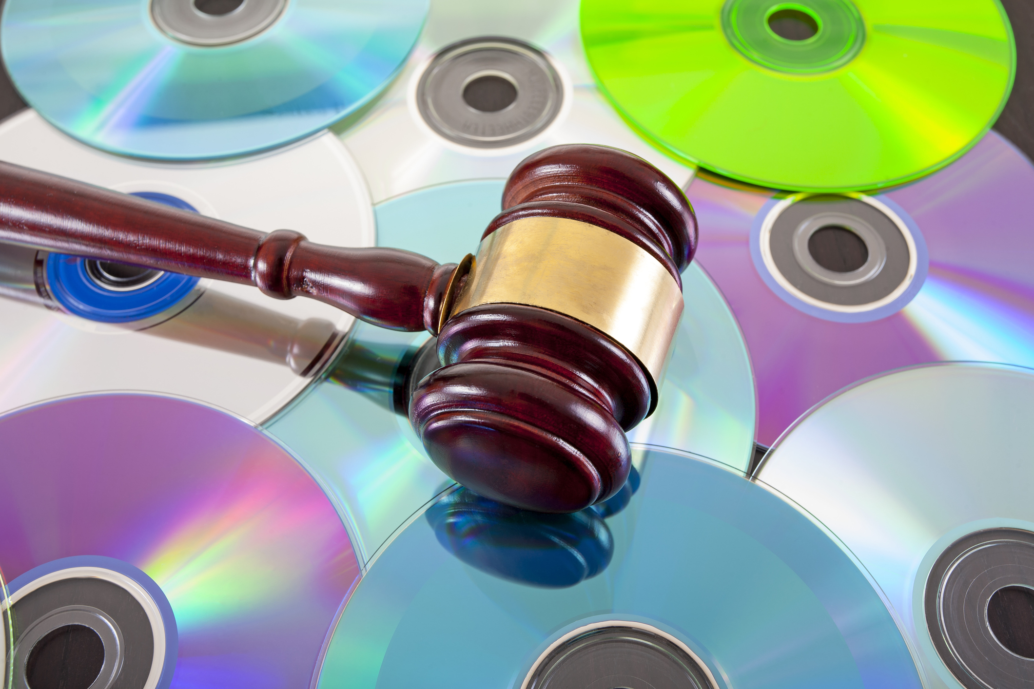 A judge's gavel resting on a pile of CD disks.