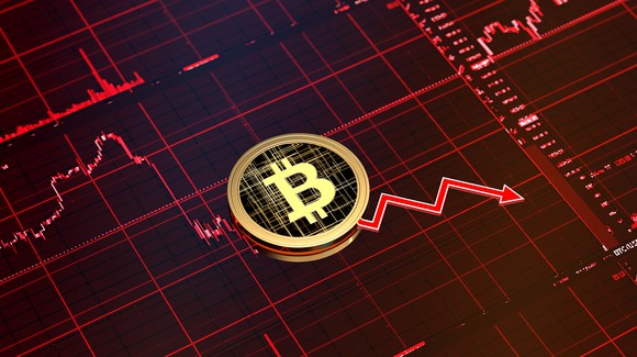 Bitcoin symbol on top of a chart trending downward.
