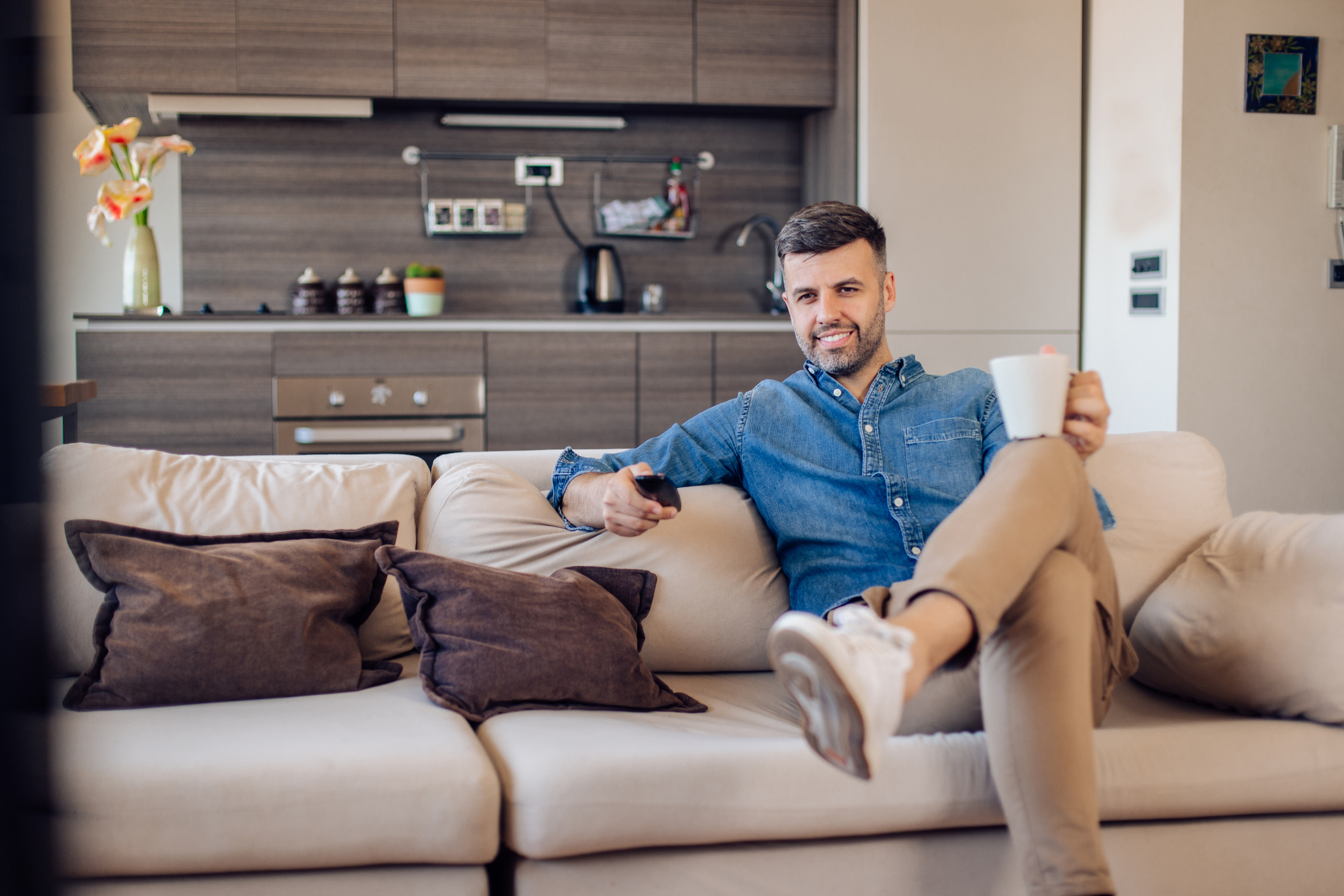Person sitting on couch with a cup of coffee in their hand.