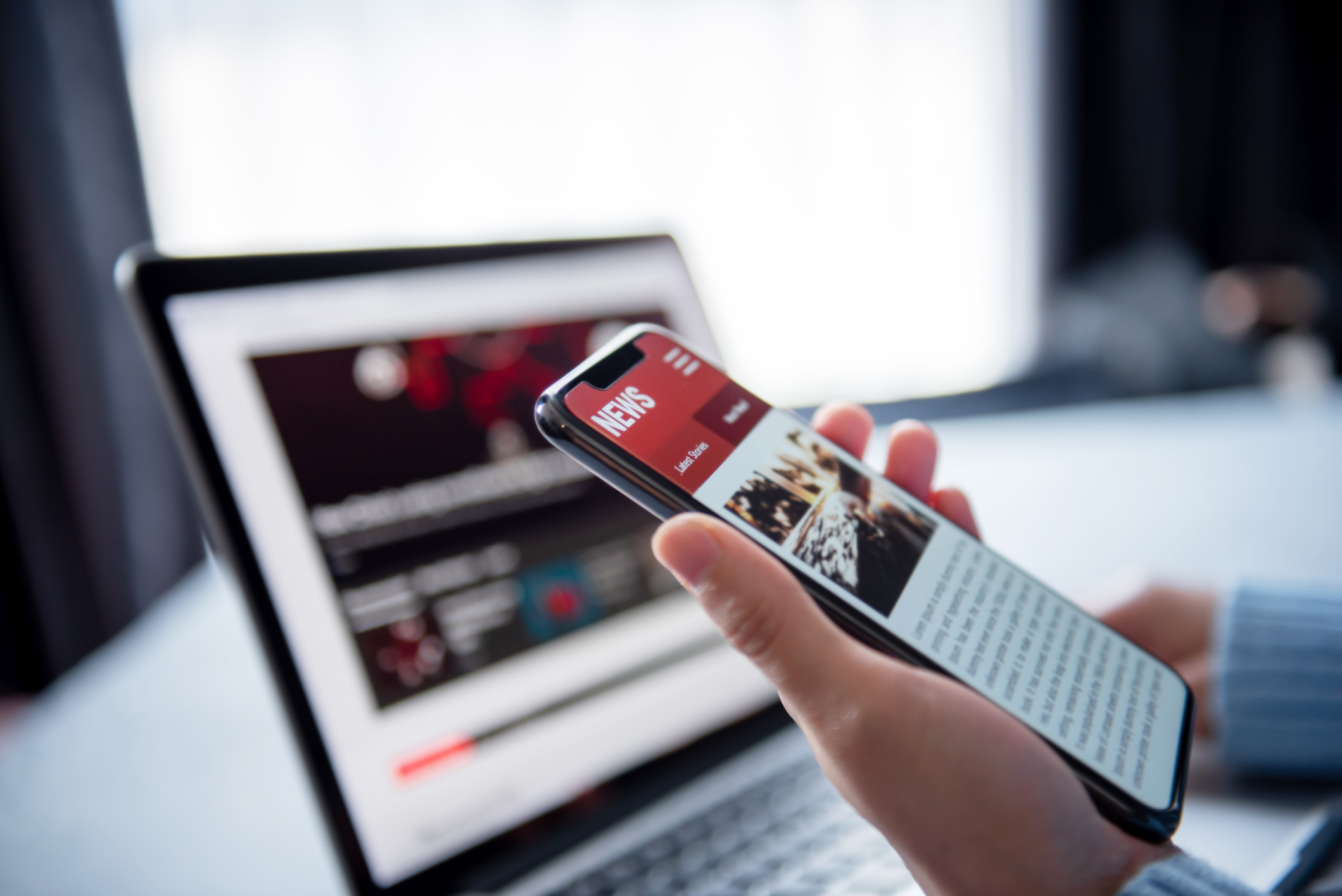 A person holding a smartphone with news app on it.