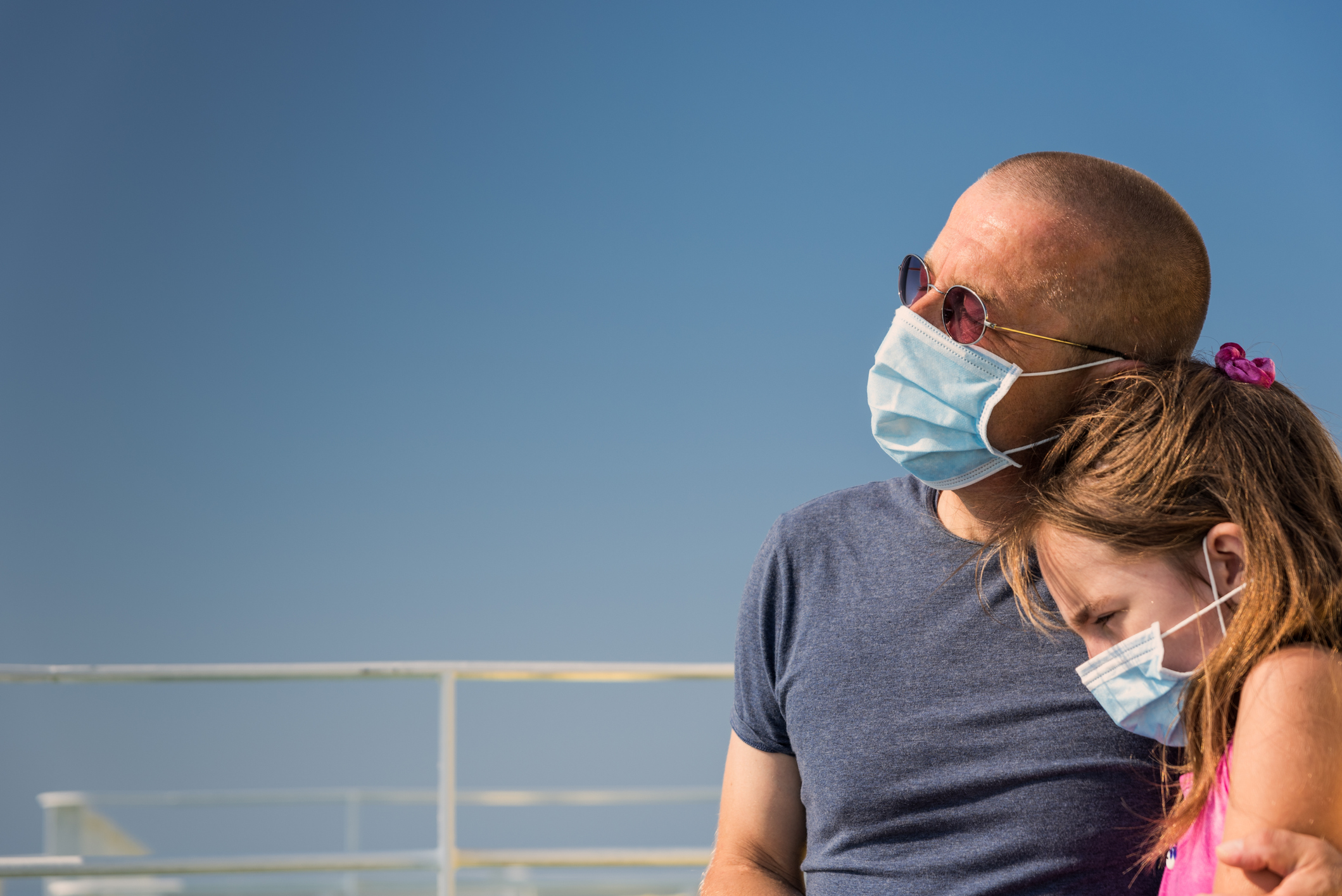 Dad consoling daughter on a cruise ship with both wearing masks.