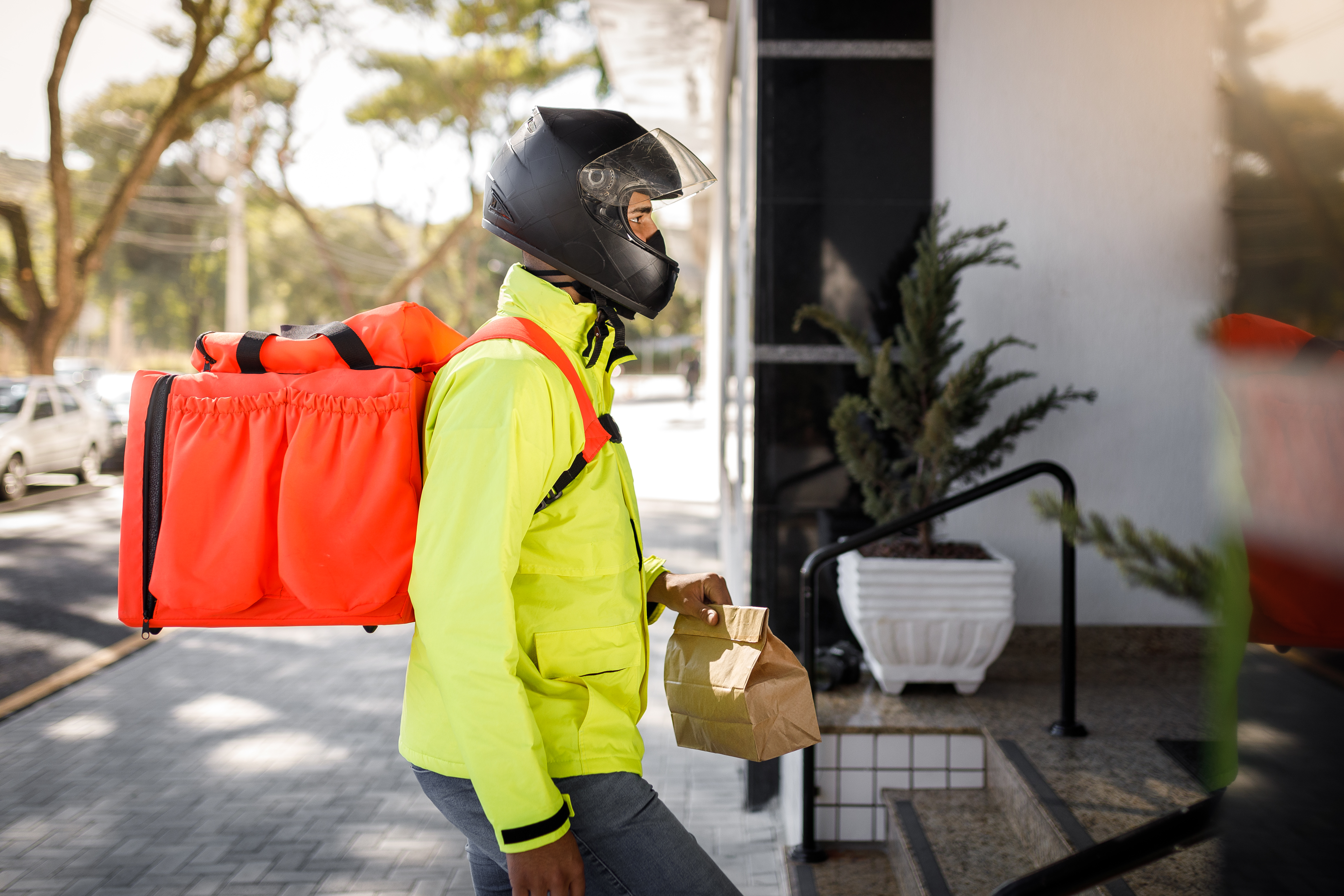 A delivery rider delivering food in a bright yellow jacket.