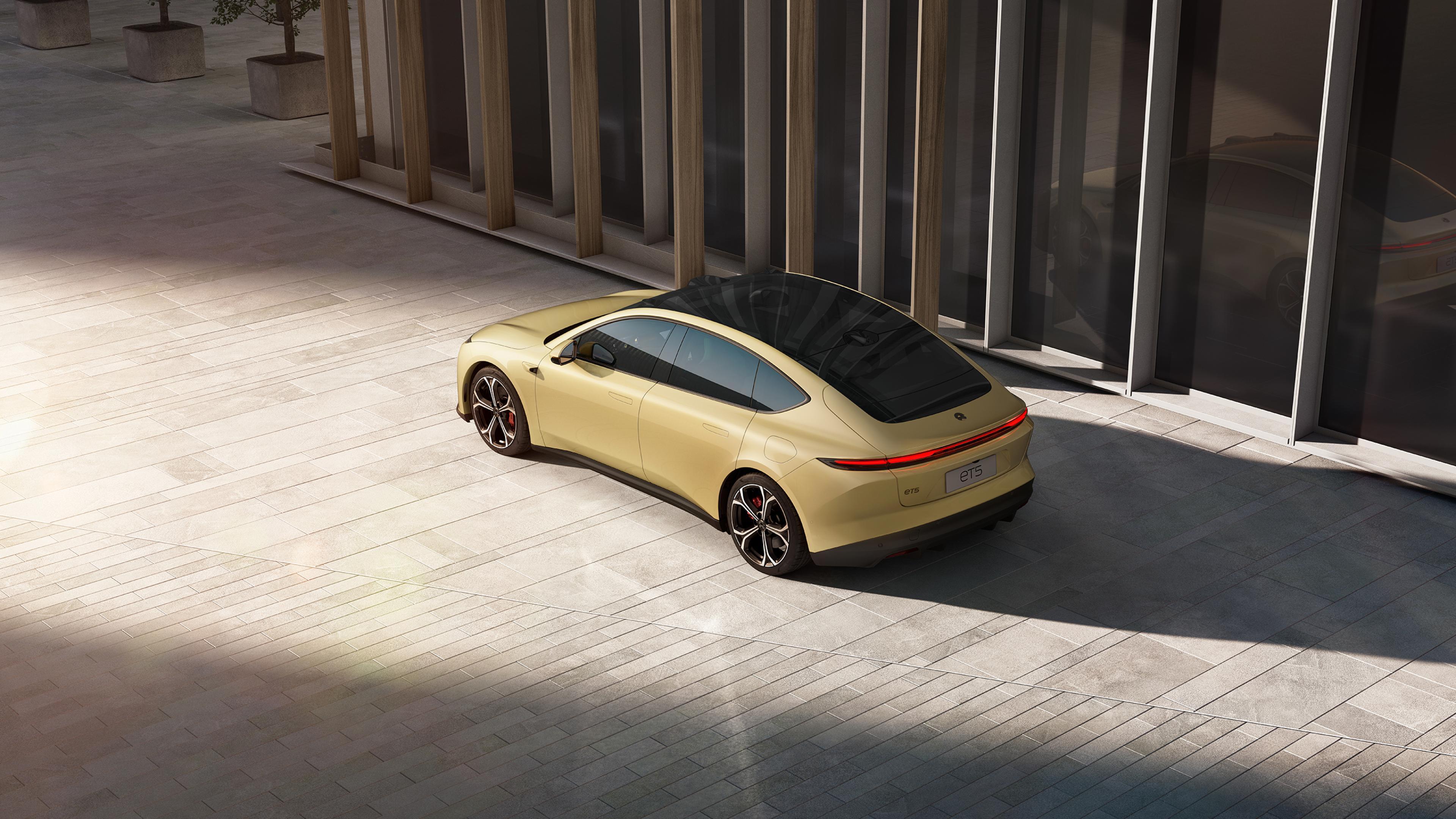 A gold Nio ET5 electric sedan in front of showroom.