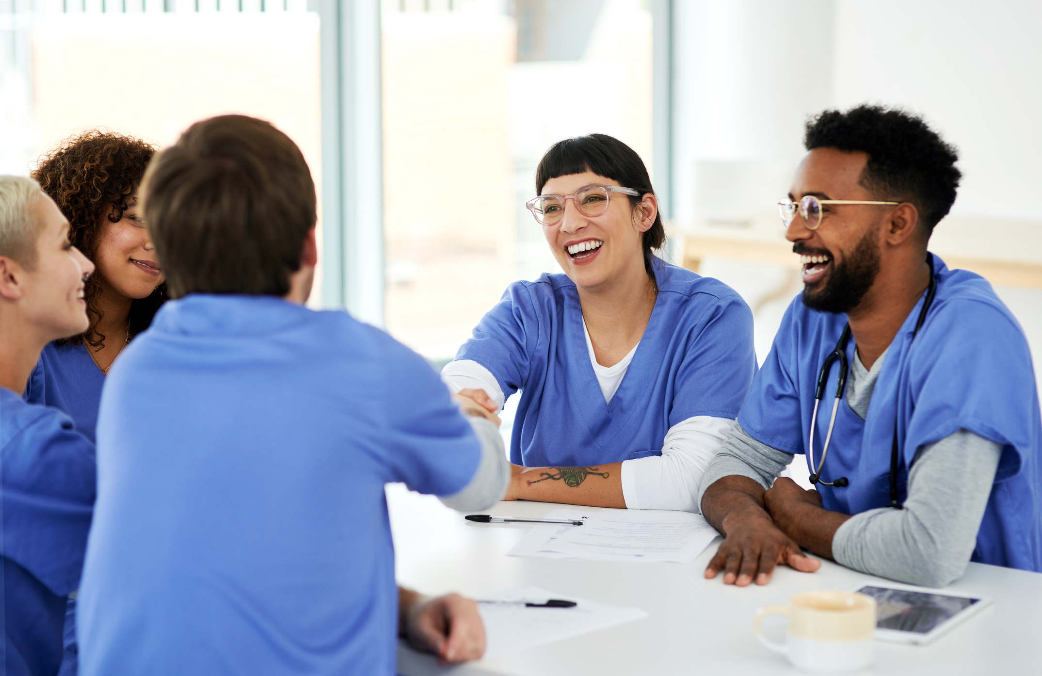 two healtchare workers shaking hands in a group. 