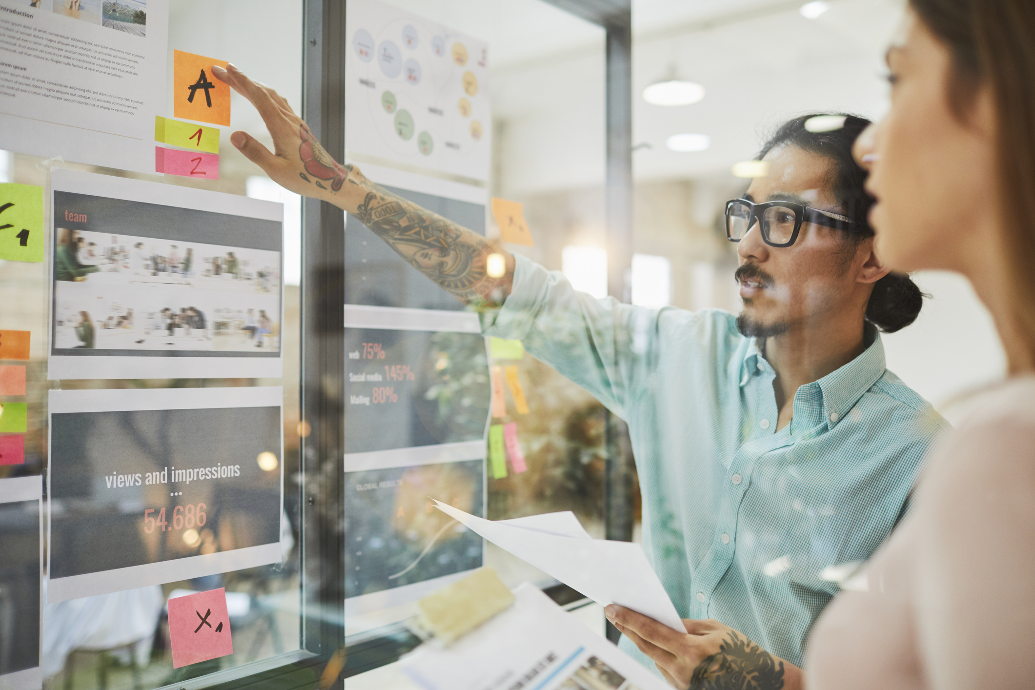 People looking at papers hung on glass wall