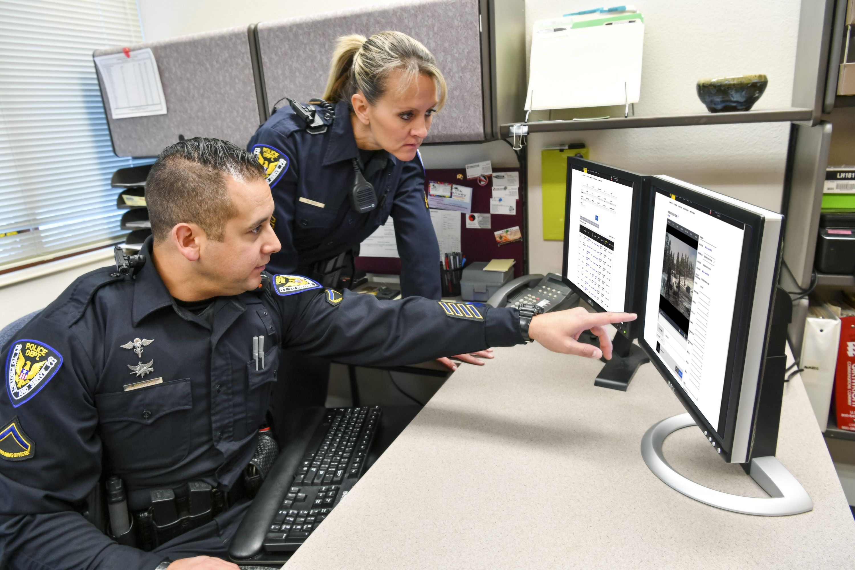 Two law enforcement officers review evidence on a computer.
