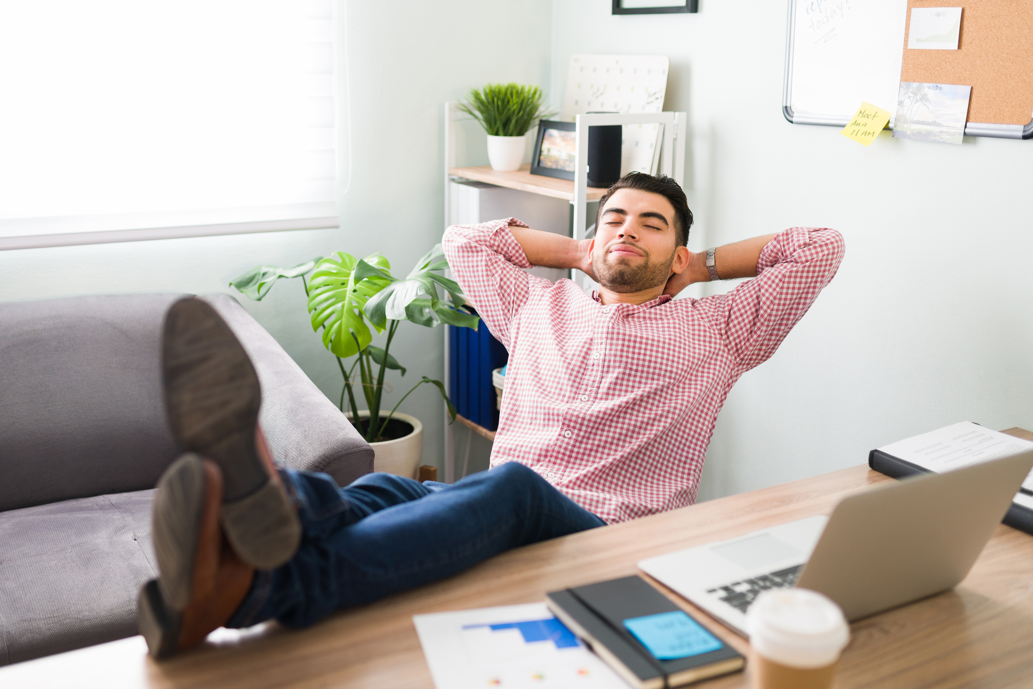 A satisfied-looking person relaxes with their feet up on a desk.