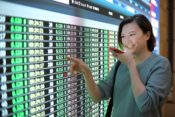 A person talking on a phone looking at an electronic wall of numbers. 