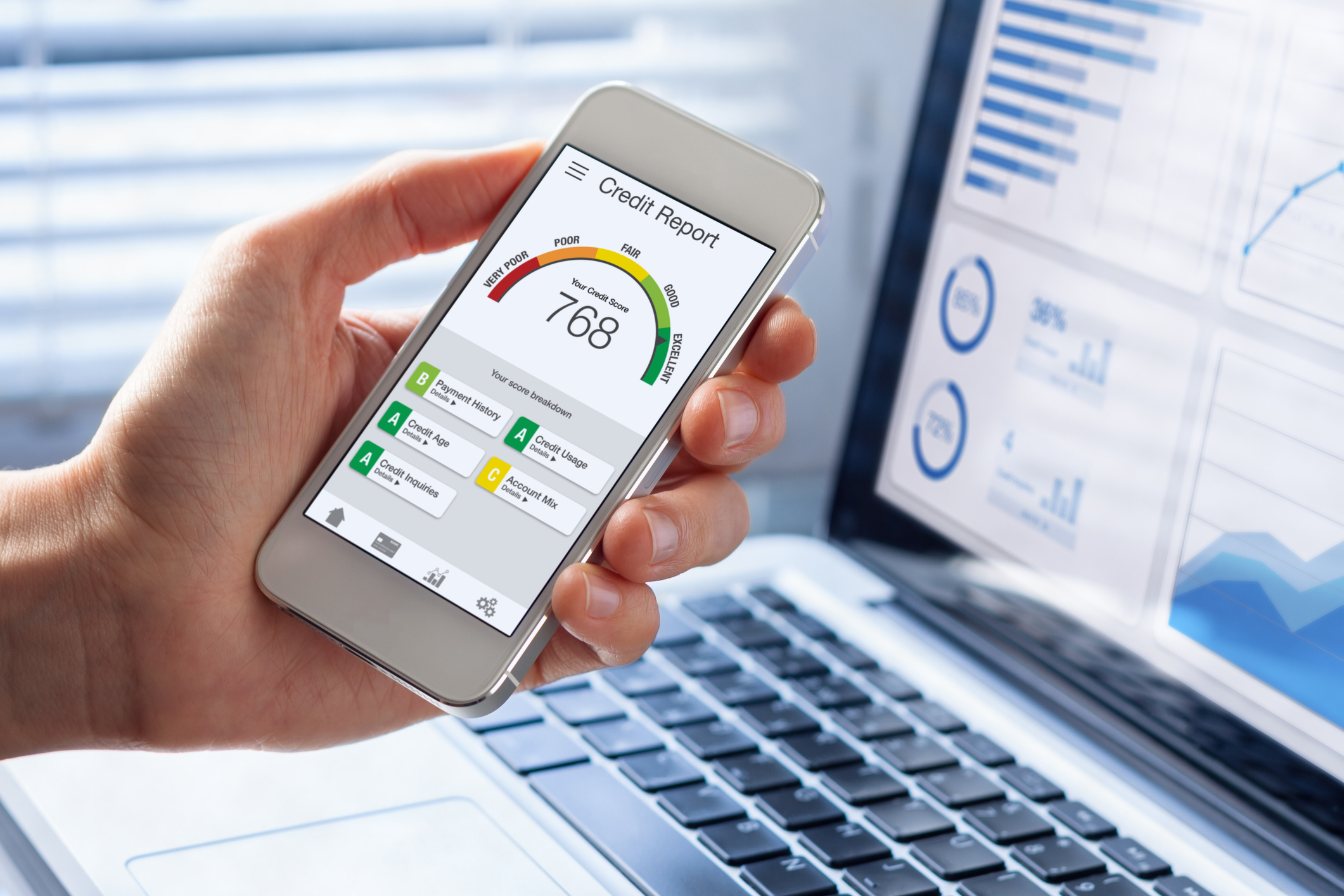 A hand holds a phone, which shows a credit score report.