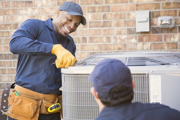 A technician servicing an air conditioning compressor. 