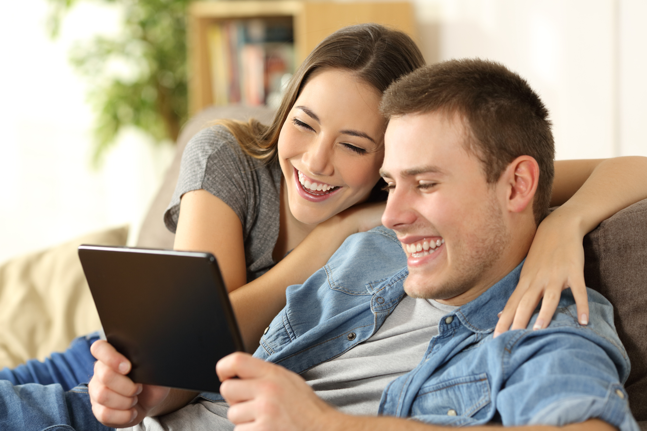 A man and a woman looking at a tablet and smiling.
