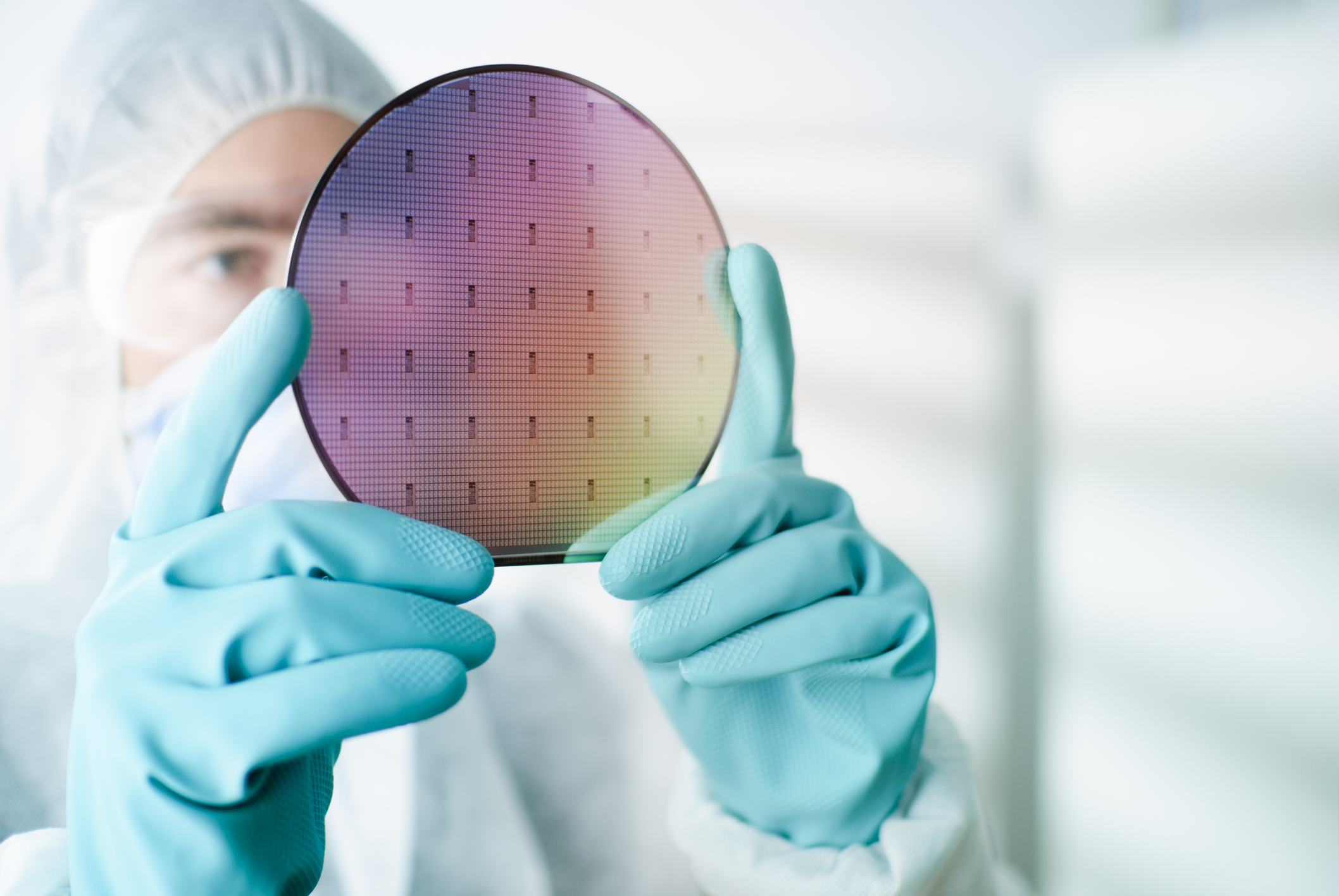 A lab worker inspecting a silicon wafer used to make computer processors.