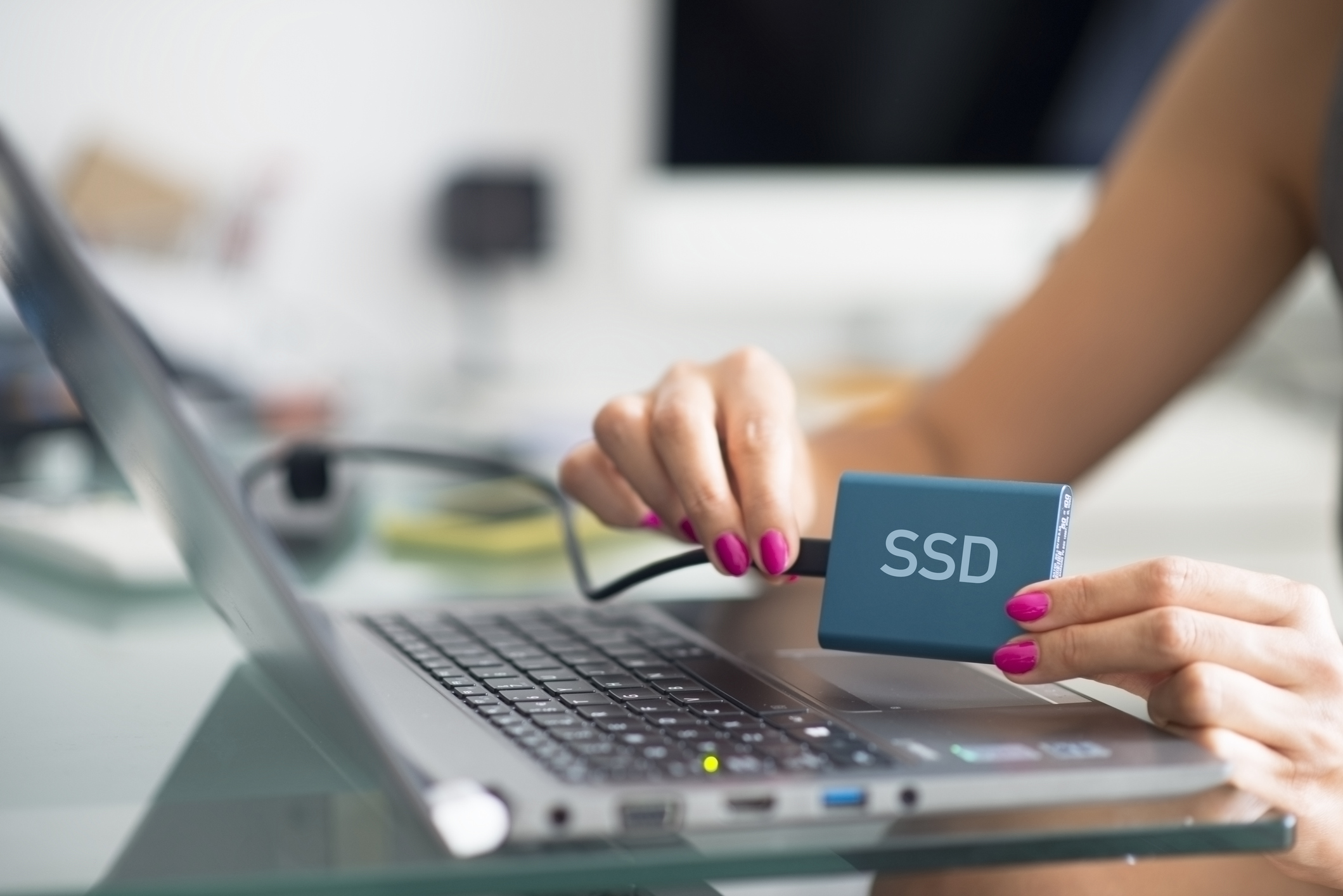 A computer user holding a storage drive with SSD printed on the side of the device.