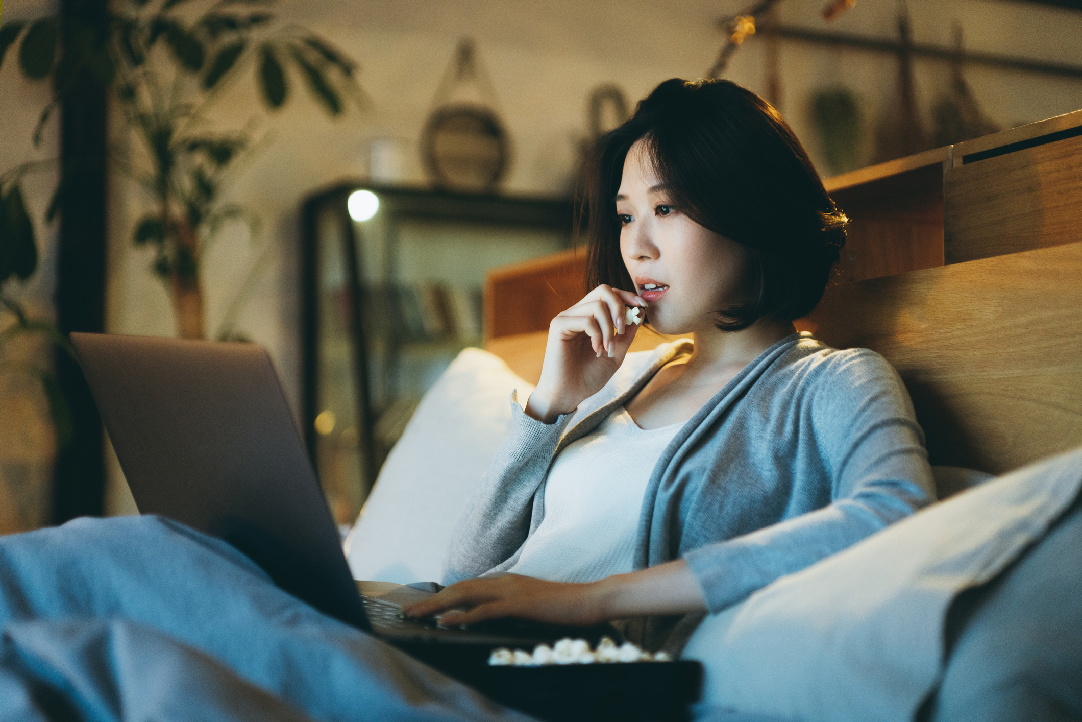 Person sitting on a couch and watching a TV show on a laptop.