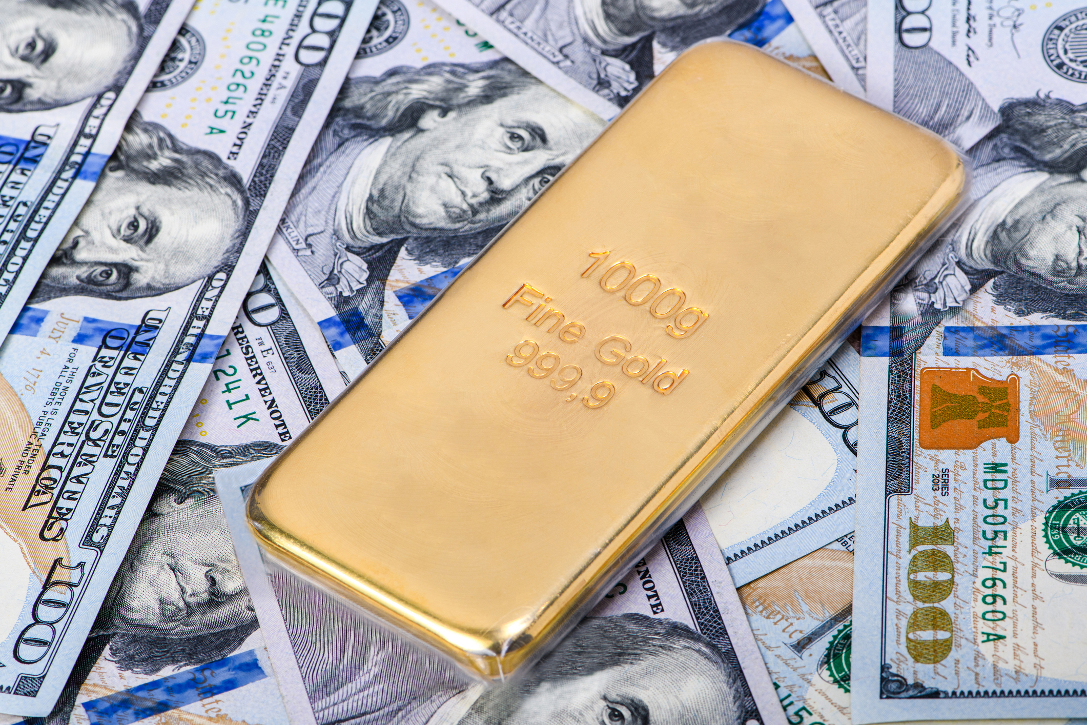 A gold bar on one hundred dollar bills.