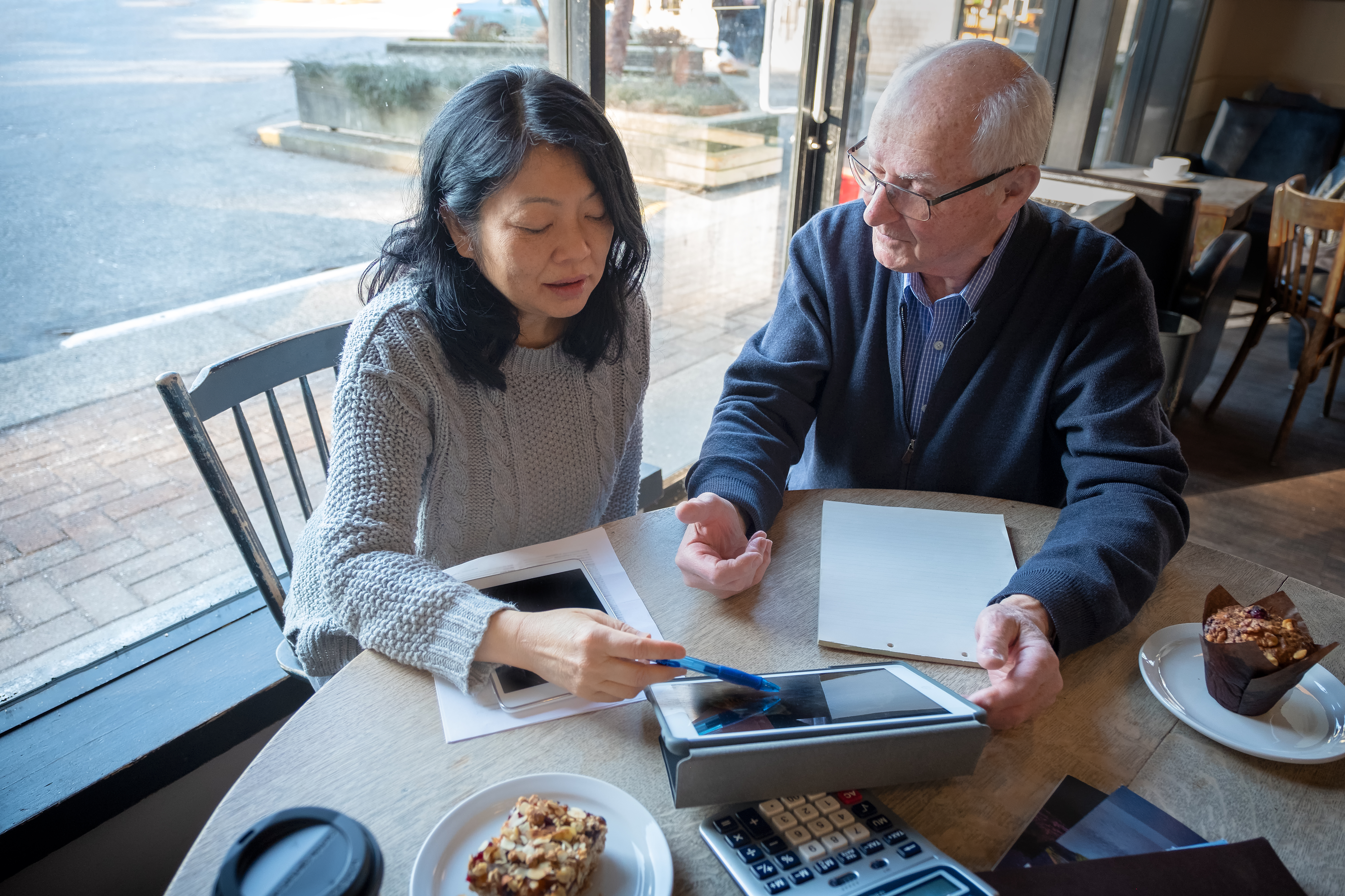 Two people reviewing finances on a laptop at a breakfast table.