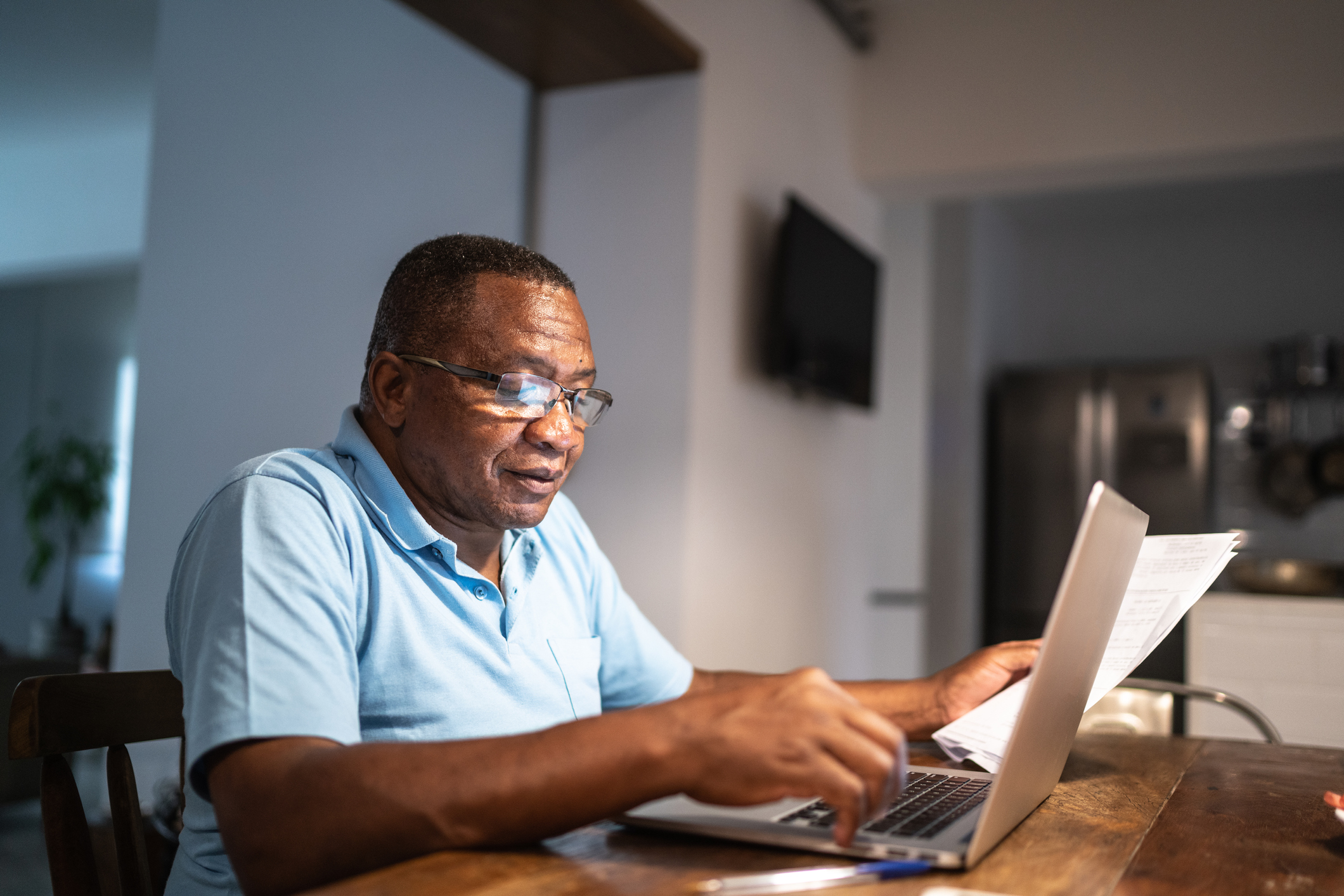 A person at a laptop holding papers.
