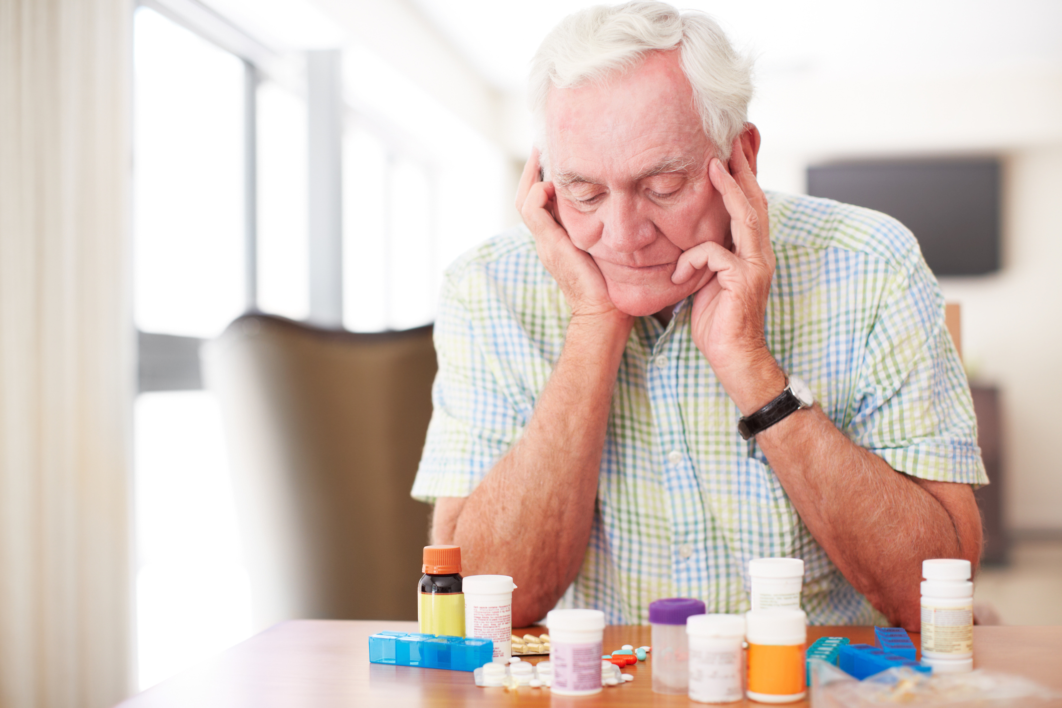An older person looking at a bunch of pills.