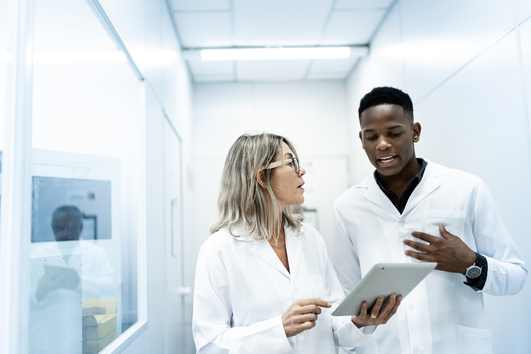 Two people looking at a tablet and talking in a laboratory setting.