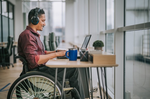 A person wearing headset while using a laptop.