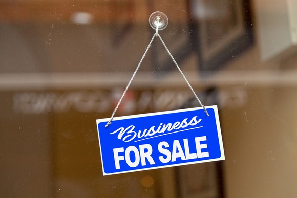 A business for sale sign hanging in a window.