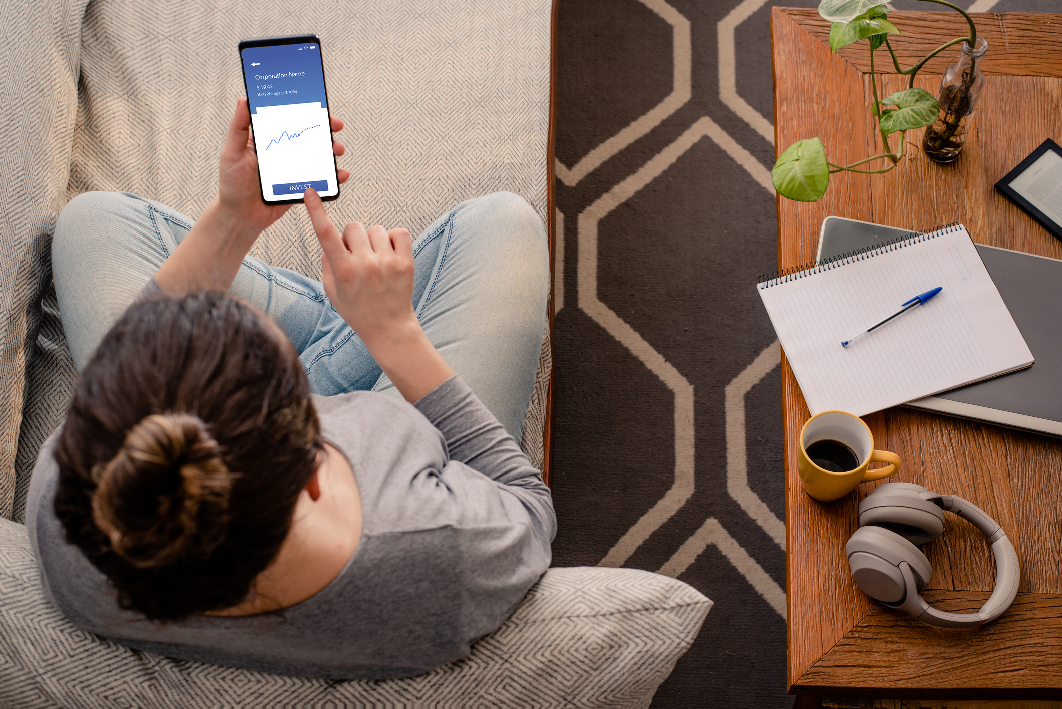 Person sitting on couch and using mobile brokerage app.