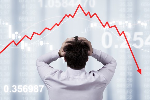 Person holding head while watching a stock chart drop. 