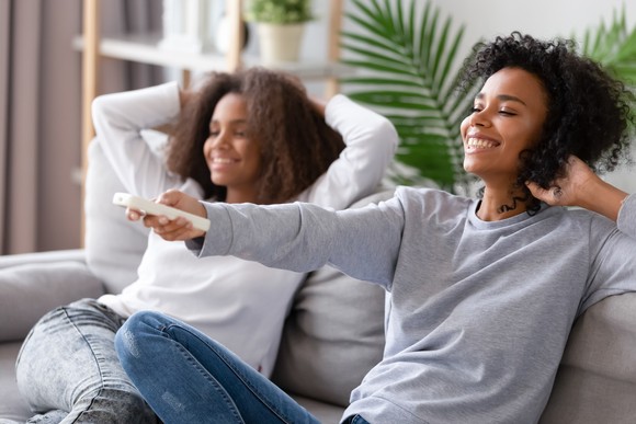 Two women on couch with remote