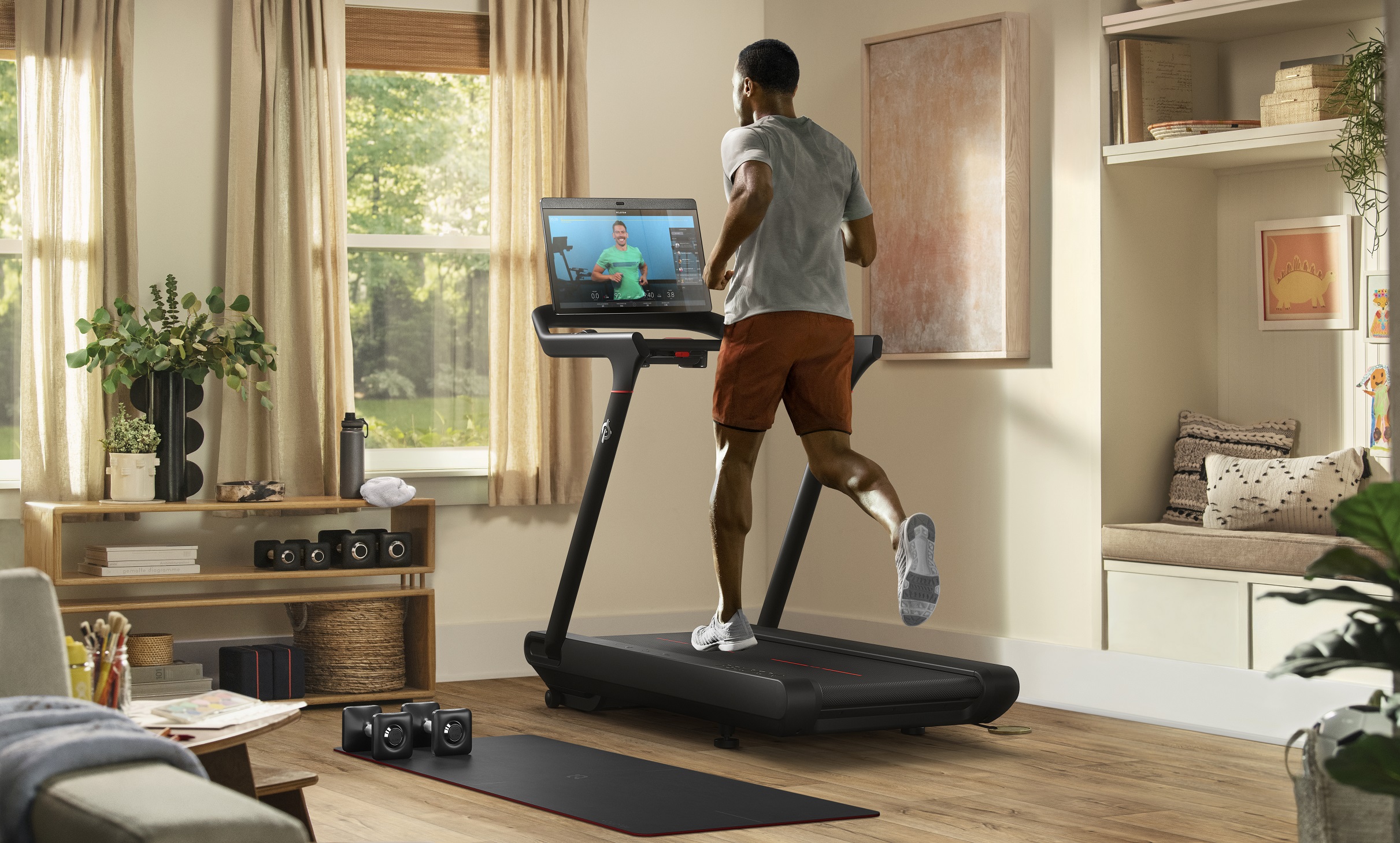A person running on a Peloton treadmill watching a video workout.