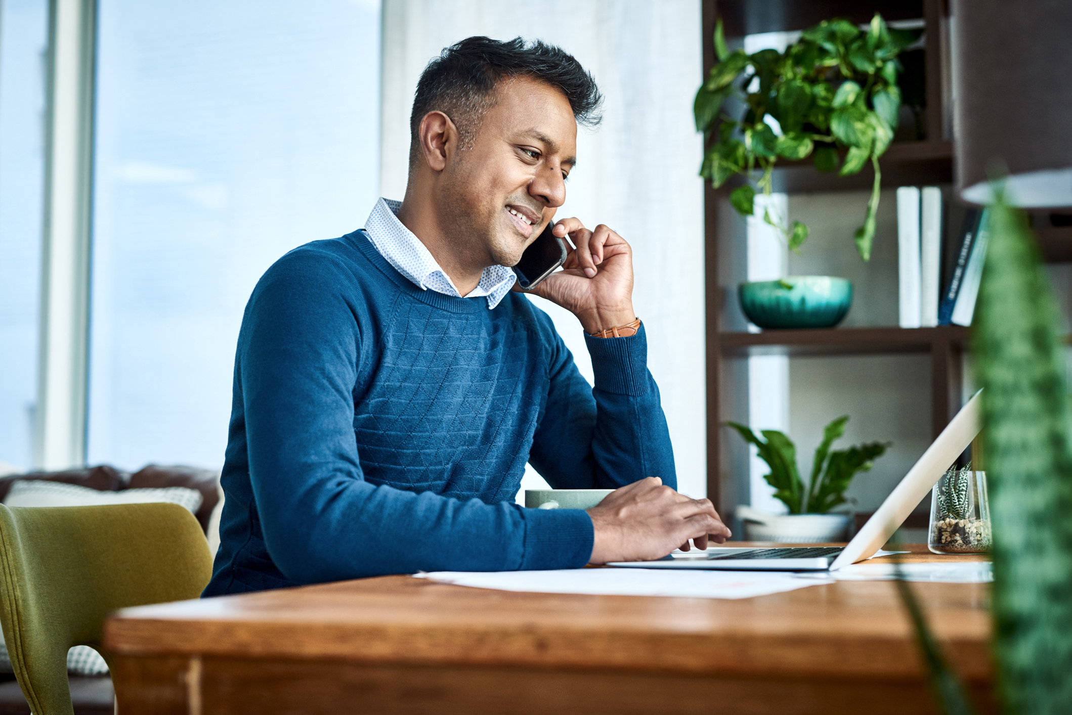 Businessman using a laptop and smartphone while working from home.