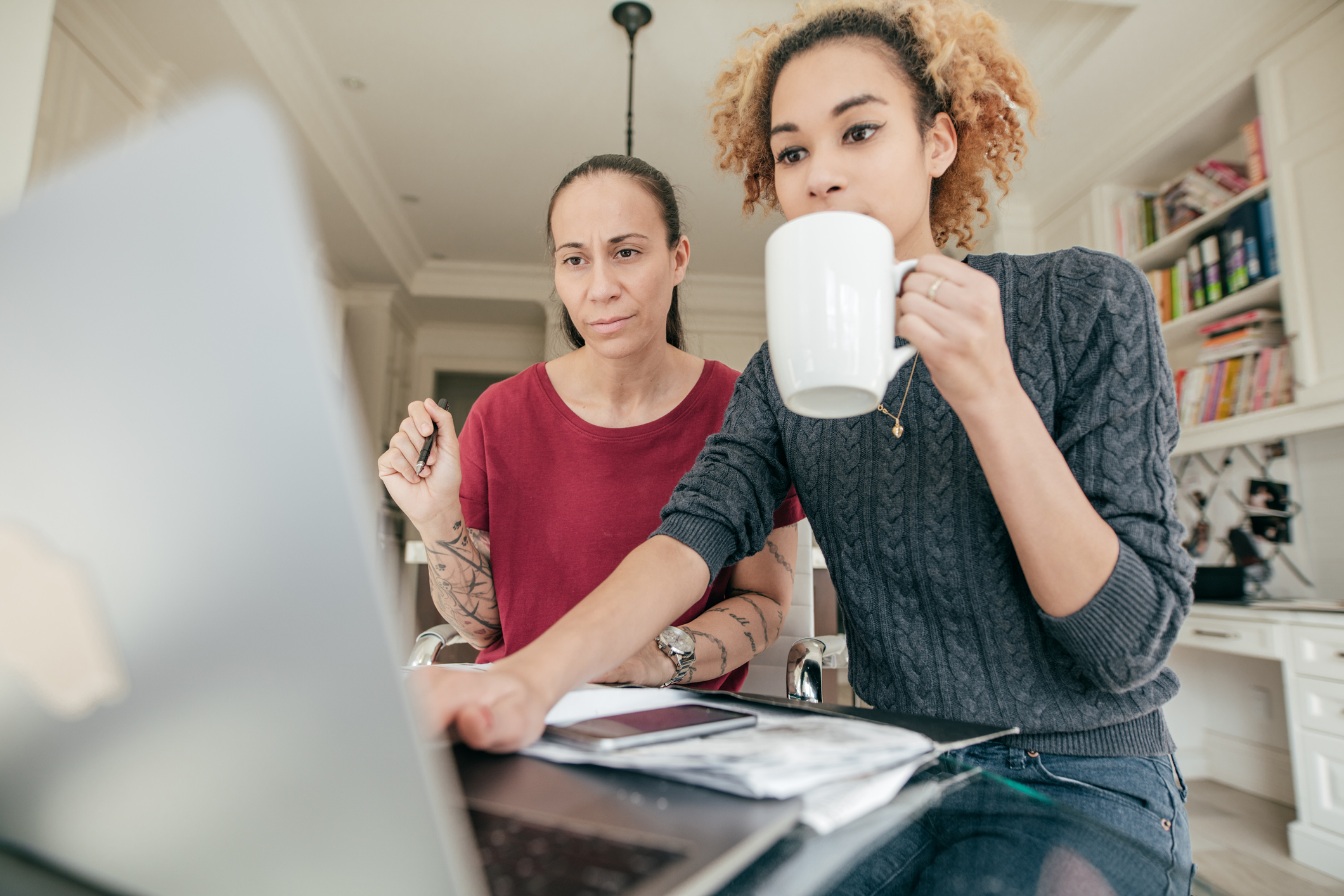 Two people look at a computer in a home office.