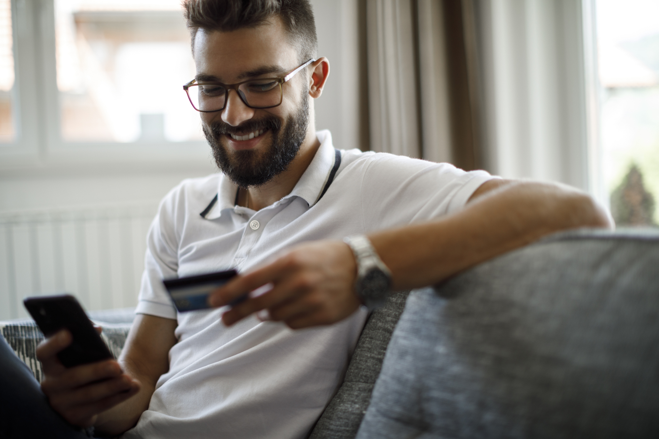 A smiling person shopping online with a credit card.