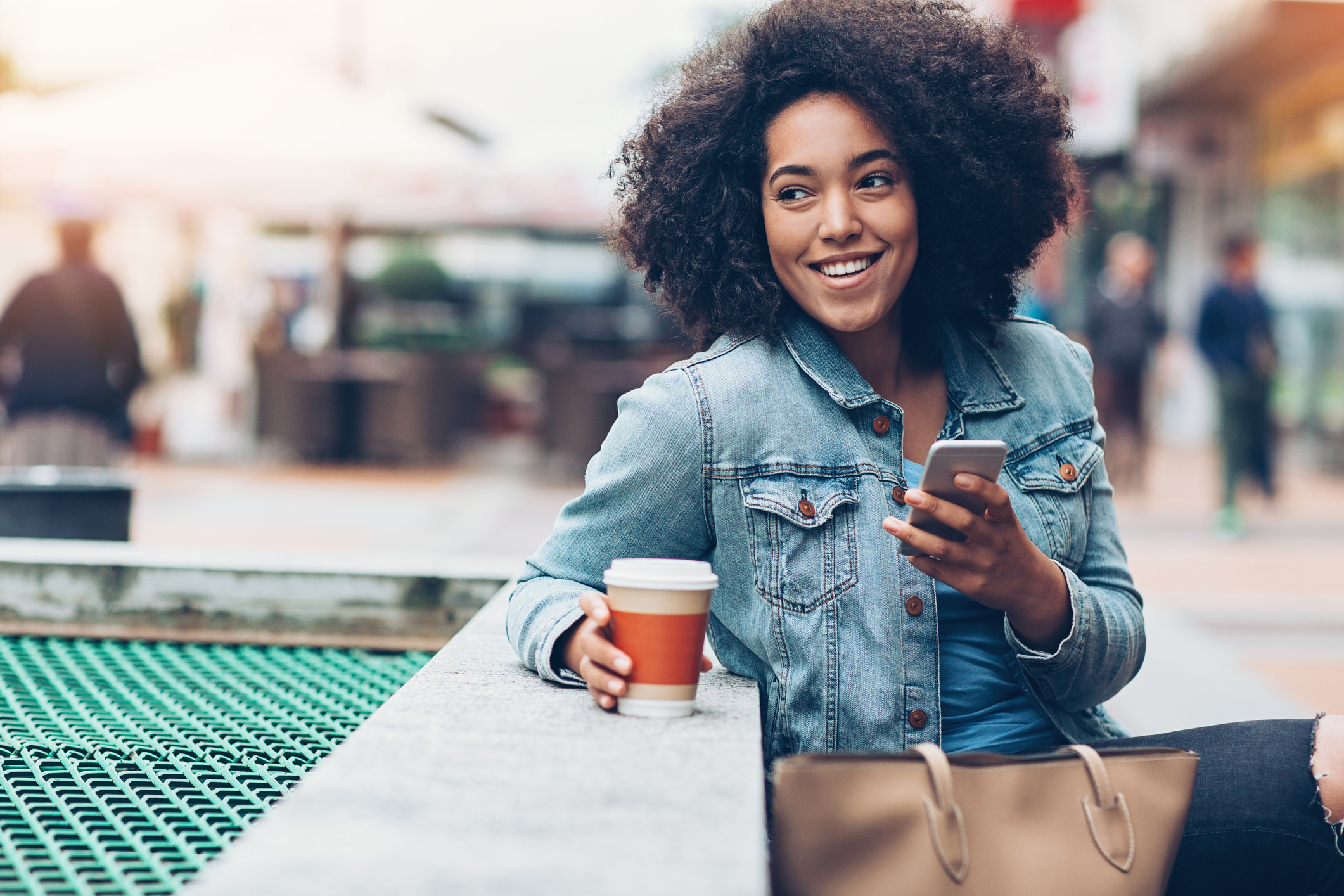 A person holding a smartphone and drinking coffee.