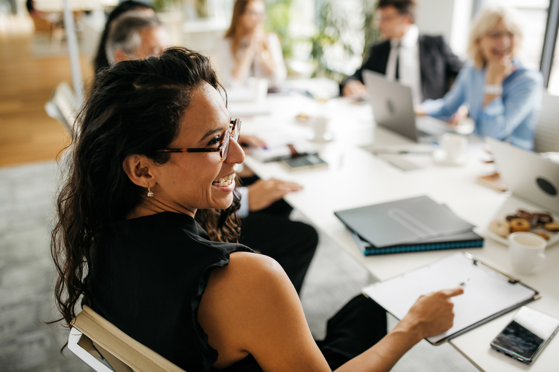 Profile of bespectacled executive laughing during a meeting.