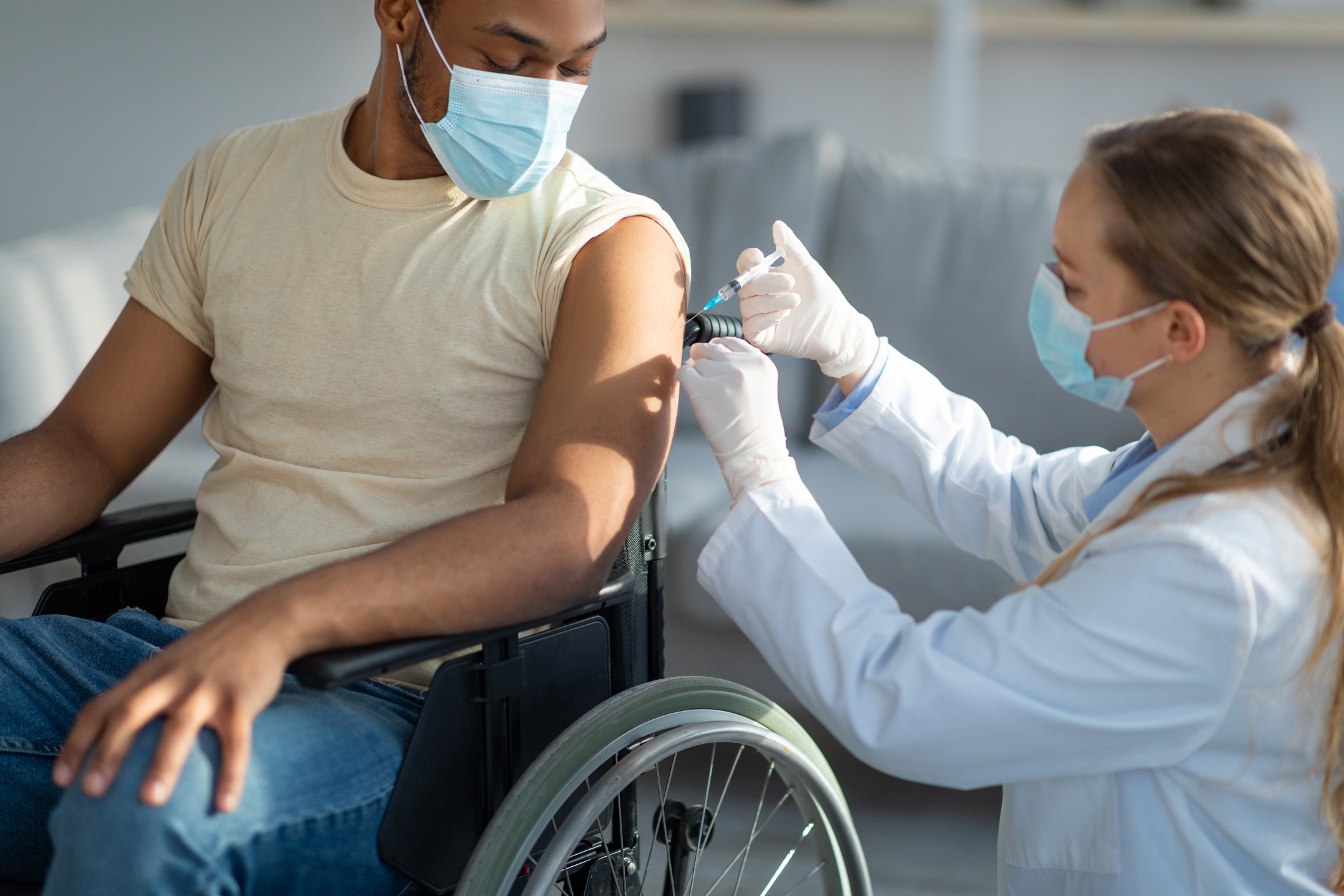 A healthcare worker vaccinates a person who uses a wheelchair.