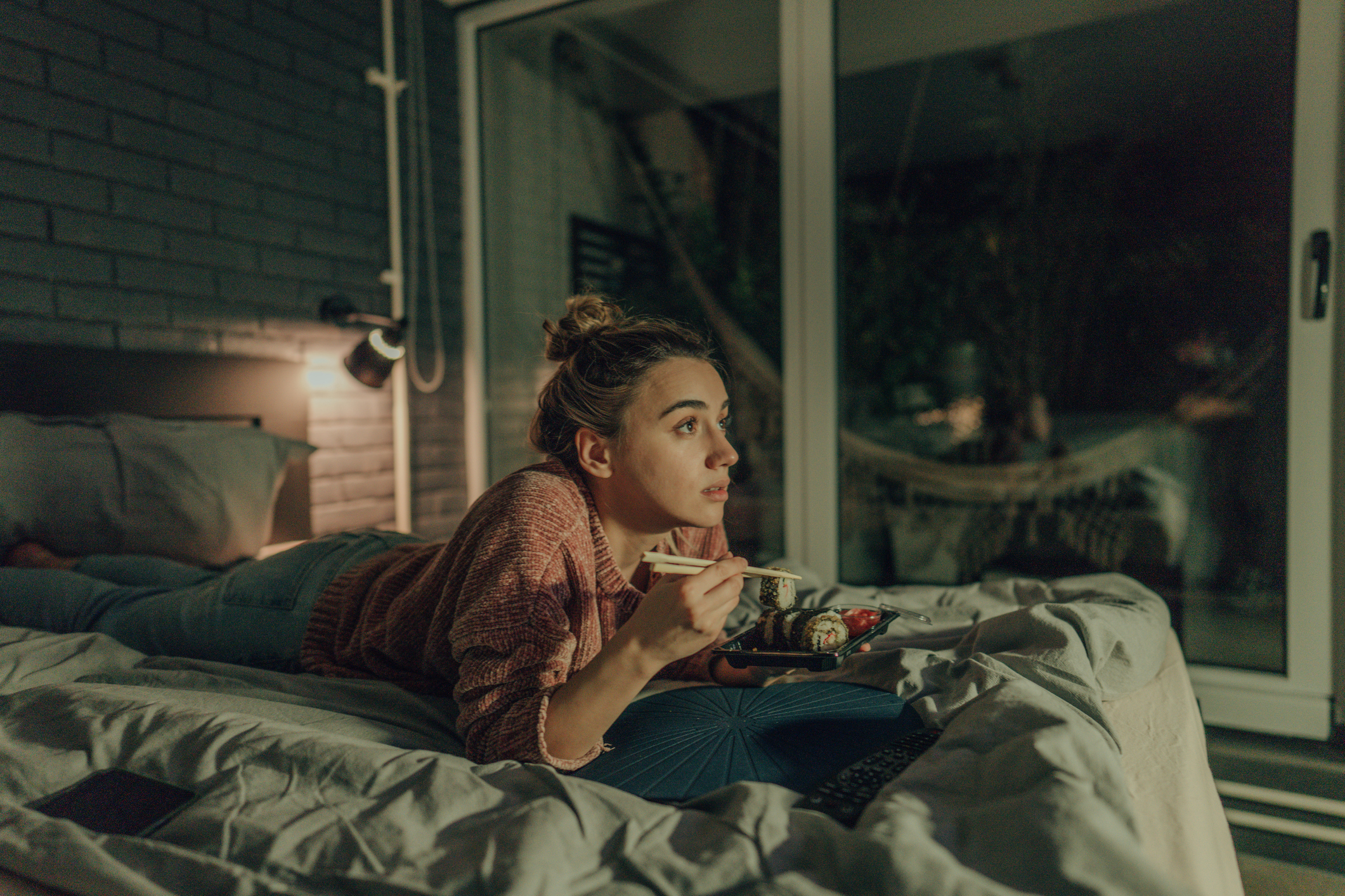 A woman watches TV in her bedroom.