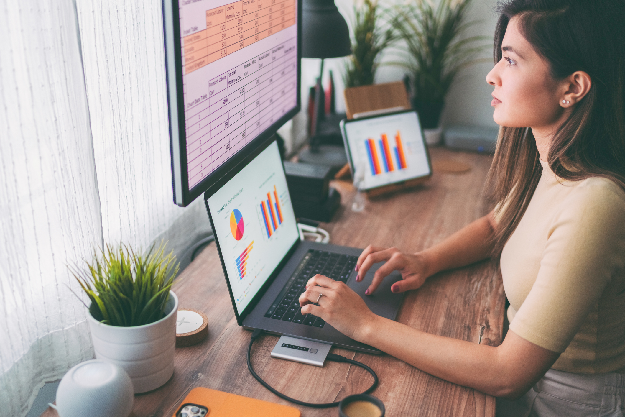 A person sits at a computer working on charts and graphs.
