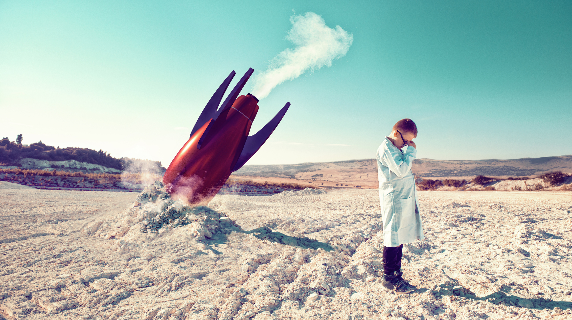 Boy in a lab coat is crying next to a crashed rocket.