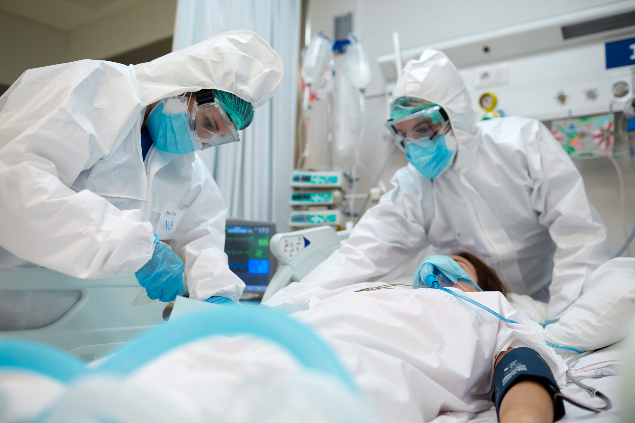 Masked doctors try to help a patient in the ICU.