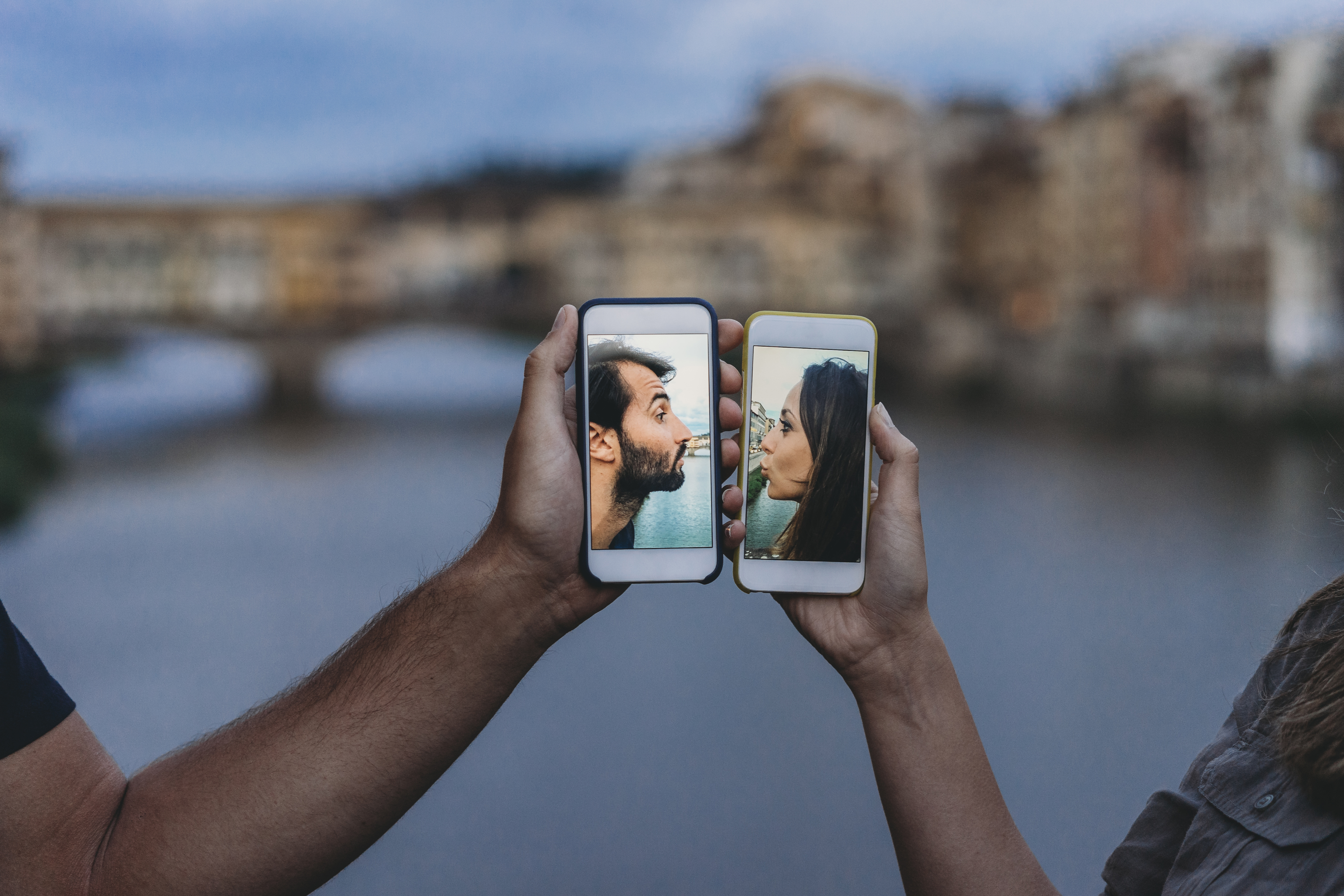 A couple kissing digitally with 2 phones.