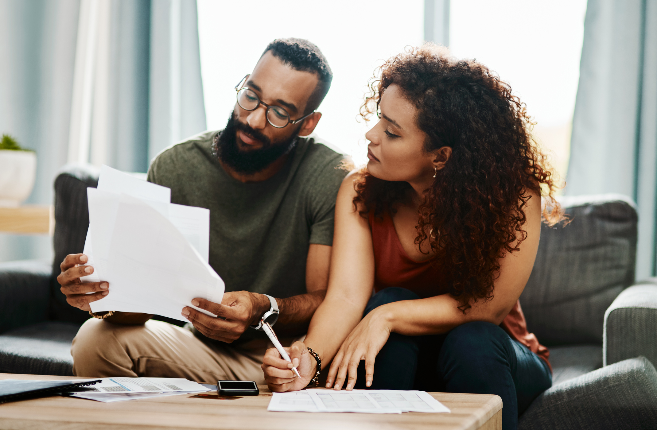 Two people on a couch, examining several papers.