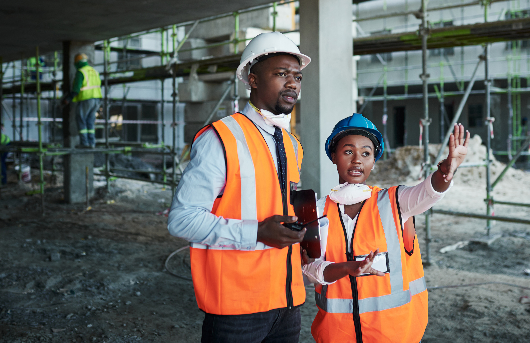 Two workers wearing safety gear at a construction site.