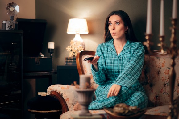 A person holding a remote while watching TV.